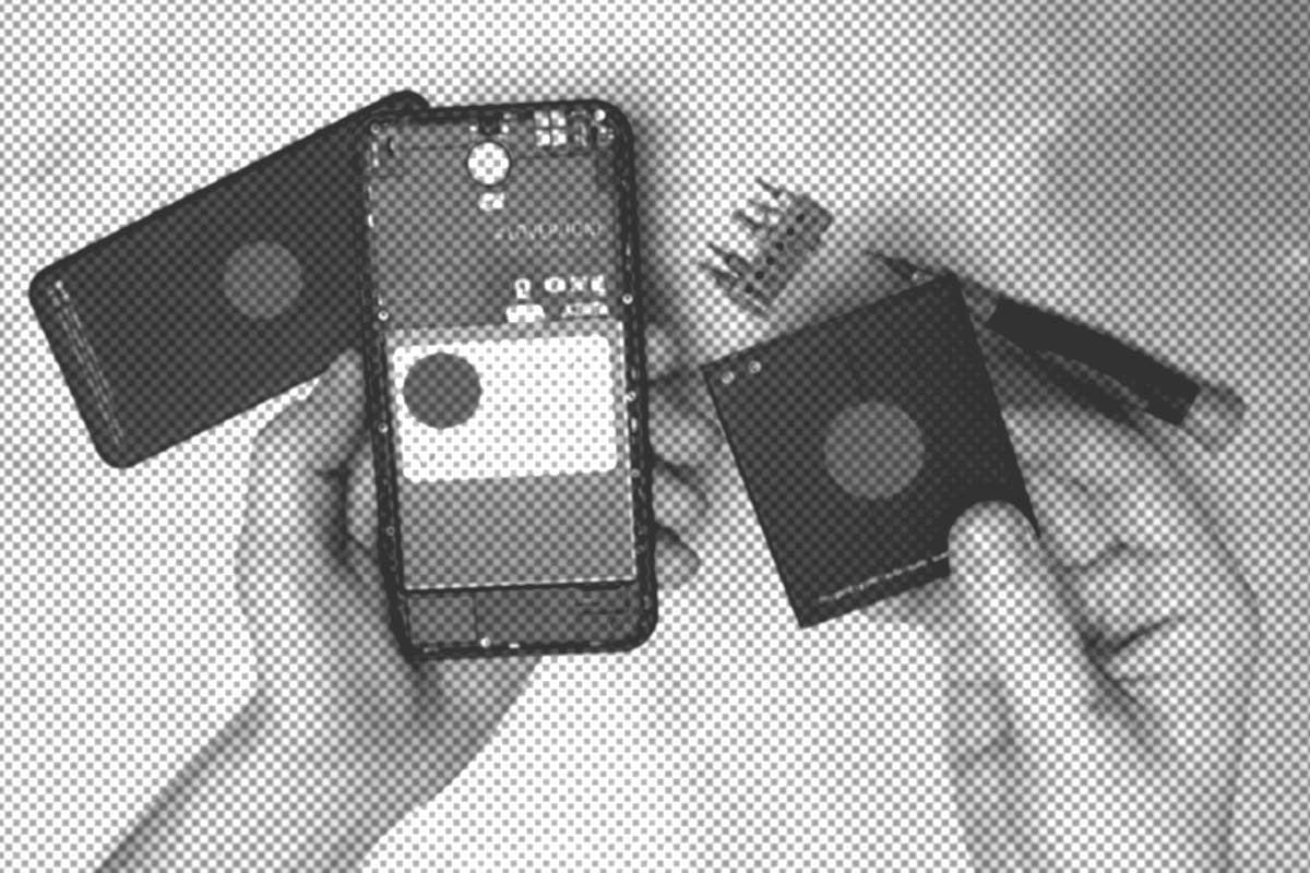 Hände halten ein Smartphone und einen entfernten Akku, daneben liegen ein Schraubenzieher und Schrauben auf einer weißen Fläche.