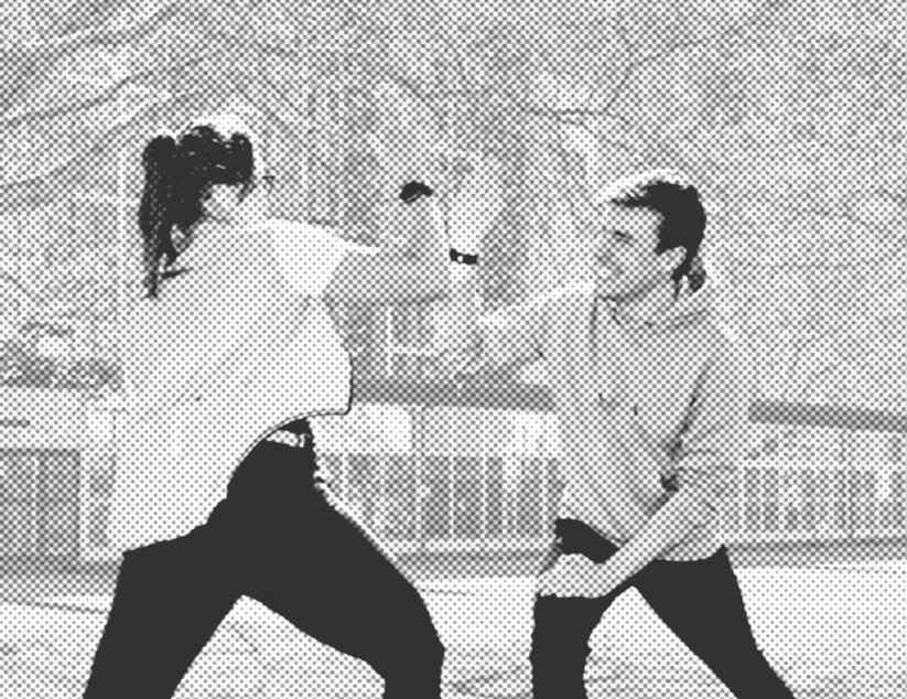 Zwei junge Menschen im Park geben sich ein High Five während sie Dehnübungen machen.