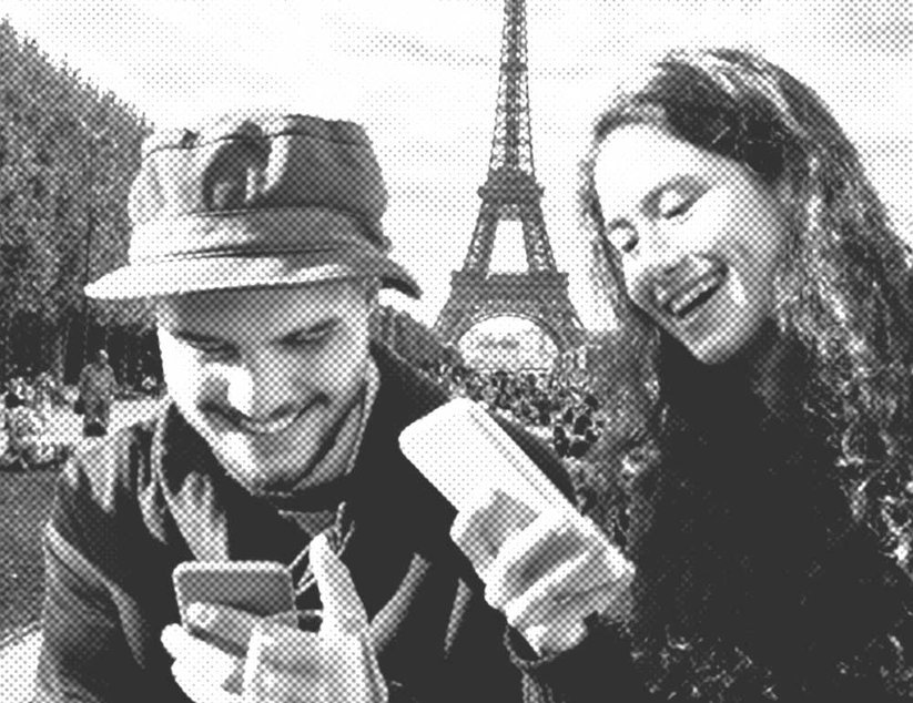 Zwei Menschen lächeln und schauen auf ihre Smartphones, im Hintergrund der Eiffelturm.