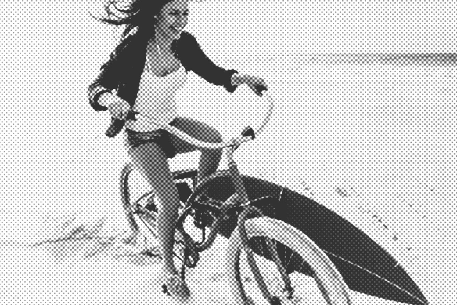 EasyTravel, Eine lachende Frau fährt am Strand auf dem Fahrrad und transportiert ein Surfbrett