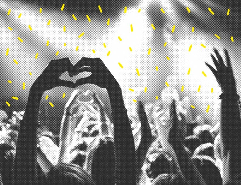 Handsilhouetten bilden ein Herz und winken bei einem Konzert mit gelbem Konfetti und Bühnenlichtern im Hintergrund.