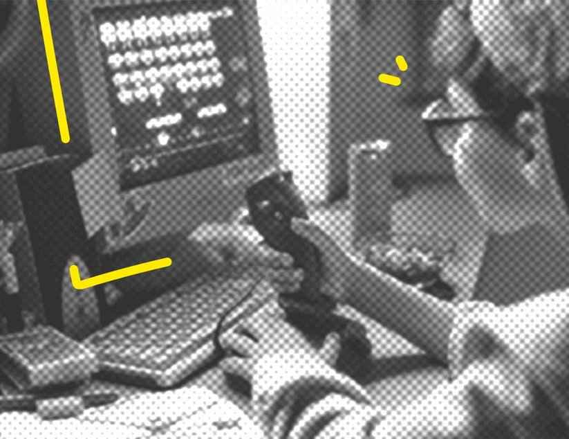 Ein Junge mit Brille sitzt vor einem alten Computer und bedient dabei einen Joystick