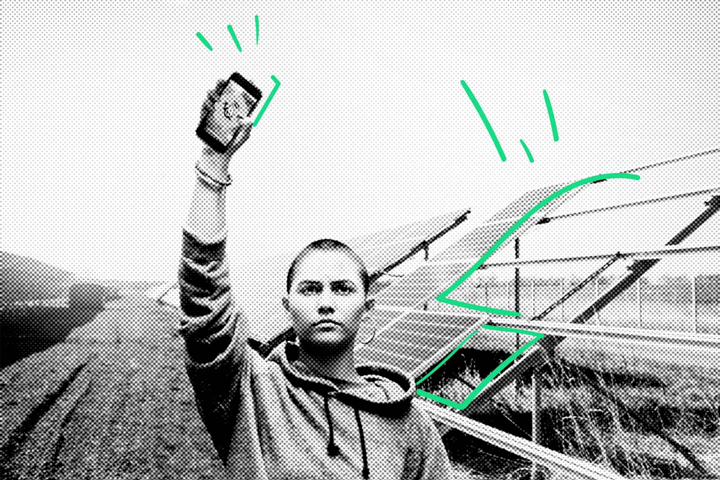 Eine Person steht vor Solarmodulen und hält mit einer Hand ein Smartphone hoch. Um das Telefon und entlang der Solarmodule sind grüne digitale Linien eingezeichnet.