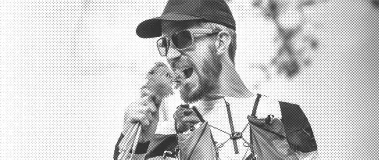 Ein Mann mit Basecap und Sonnenbrille beisst in Blumen