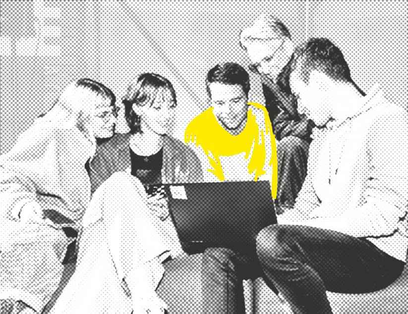 Fünf Menschen sitzen um einen Laptop herum, den eine Person auf dem Schoß hält und schauen lächelnd auf den Bildschirm.