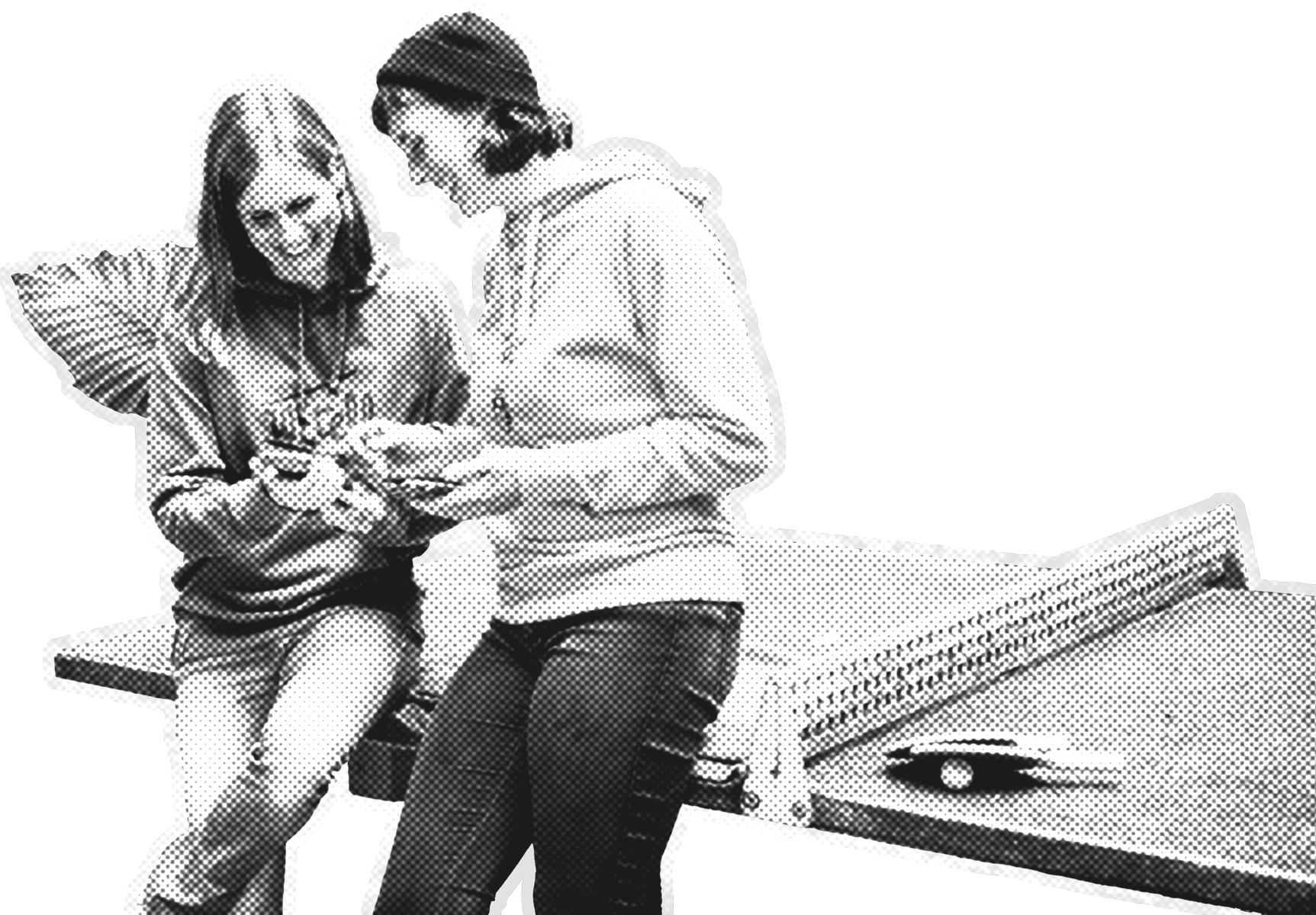 Zwei lächelnde Personen stehen an einem Tisch und schauen gemeinsam auf ein Handy in ihren Händen. Beide tragen lässige Kleidung mit Hoodies und Jeans.