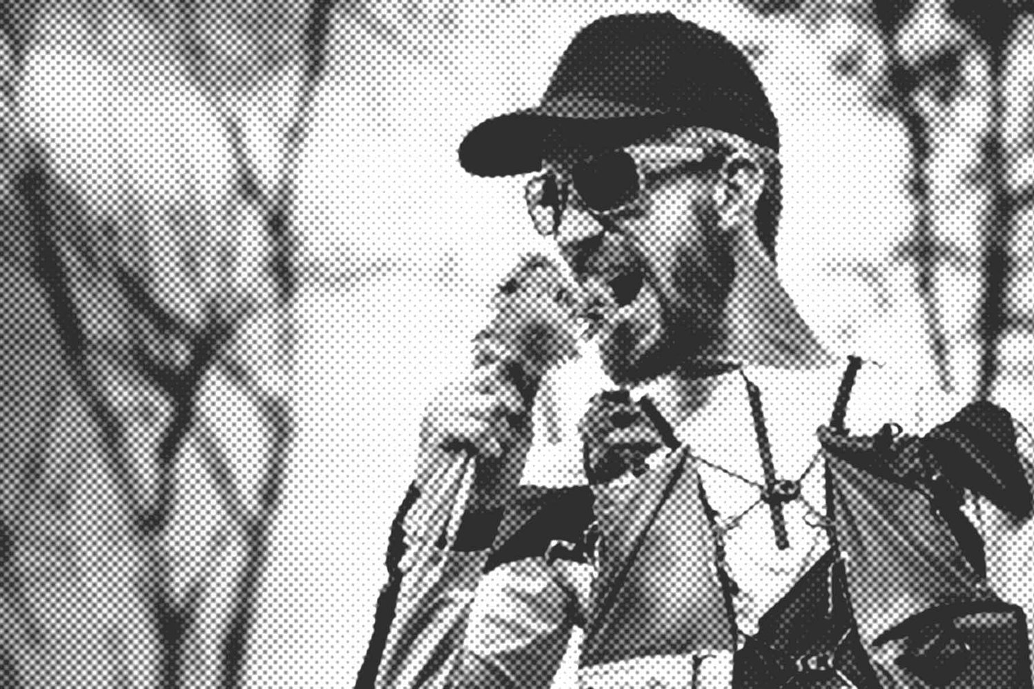OneNumber, Sportlicher Mann mit Sonnenbrille und Cap beißt in einen Strauß Blumen.
