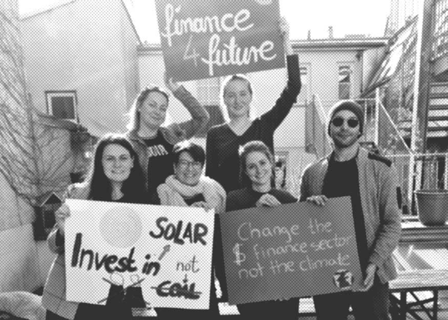 Eine Gruppe von sechs Personen hält Schilder hoch, die für nachhaltige Finanzen und die Unterstützung von Solarenergie werben.