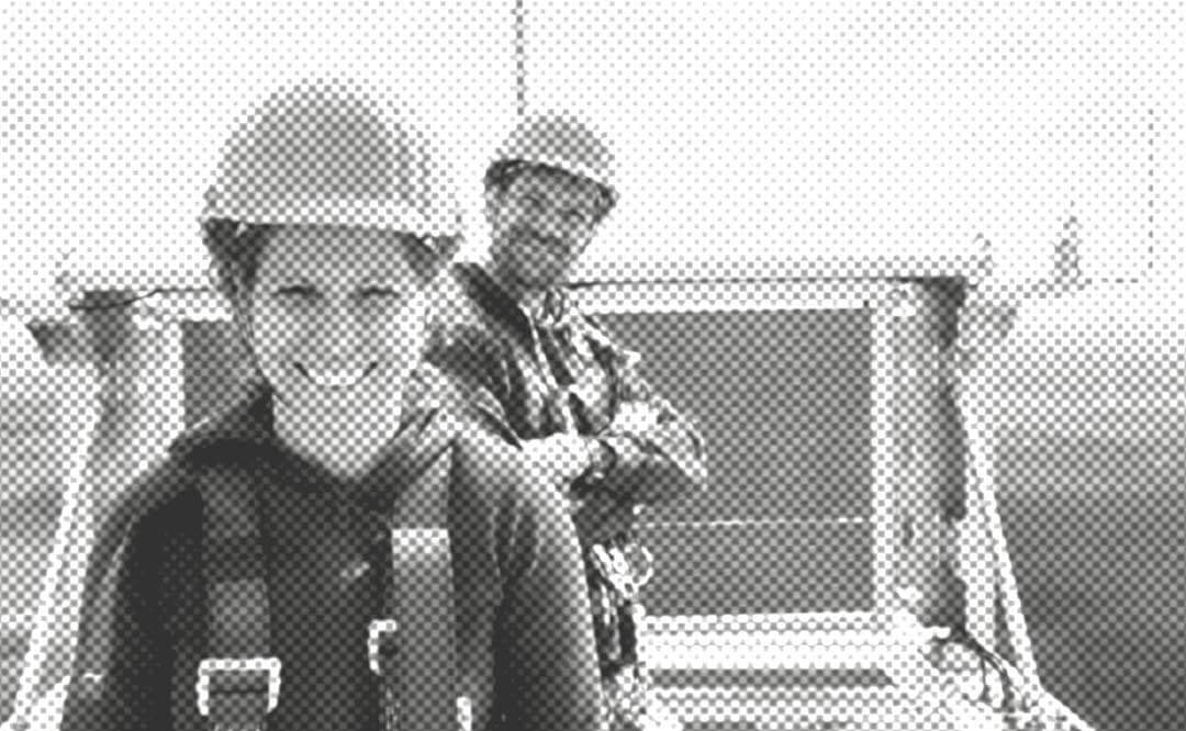 Frau und Mann auf Windkraftanlage, mit Helmen und Sicherungsgurten